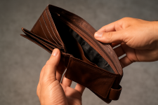Das Bild zeigt eine geöffnete Geldbörse, die von einer Hand gehalten wird. Die Geldbörse ist aus braunem Leder und wirkt gebraucht. Innen ist sie leer und zeigt keine Geldscheine oder Karten. Der Hintergrund ist unscharf und hat einen grauen Farbton, was das Augenmerk auf die Geldbörse lenkt. Die Pose der Hand und der Geldbörse vermittelt ein Gefühl der Enttäuschung oder finanziellen Knappheit. Das Bild zeigt eine geöffnete Geldbörse, die von einer Hand gehalten wird. Die Geldbörse ist aus braunem Leder und wirkt gebraucht. Innen ist sie leer und zeigt keine Geldscheine oder Karten. Der Hintergrund ist unscharf und hat einen grauen Farbton, was das Augenmerk auf die Geldbörse lenkt. Die Pose der Hand und der Geldbörse vermittelt ein Gefühl der Enttäuschung oder finanziellen Knappheit.