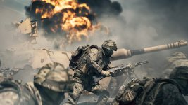 Das Bild zeigt eine dramatische Kampfszene aus einem militärischen Umfeld. Ein Soldat ist im Vordergrund zu sehen, der mit einem Gewehr in der Hand auf ein Ziel gerichtet ist. Im Hintergrund explodieren Gebäude, Rauch und Trümmer wirbeln durch die Luft, was eine intensive und chaotische Atmosphäre schafft. Weitere Soldaten sind ebenfalls sichtbar, die an der Action teilnehmen. Die gesamte Szene vermittelt einen starken Eindruck von Spannung und Kampfgeschehen, was die Spieler von Battlefield 6 ansprechen dürfte.