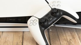 Das Bild zeigt einen modernen Videospiel-Controller in einer schwarz-weißen Farbgebung, der neben einer Spielkonsole platziert ist. Die Konsole hat ein elegantes, minimalistisches Design mit einer glänzenden Oberfläche. Im Hintergrund sind USB-Ports sichtbar, die für verschiedene Peripheriegeräte verwendet werden können. Der Boden ist aus Holz und verleiht dem Setup eine warme und einladende Atmosphäre. Der Fokus liegt auf der Verbindung zwischen dem Controller und der Konsole, was das Thema des Gamings und moderner Technologie unterstreicht. Das Bild zeigt einen modernen Videospiel-Controller in einer schwarz-weißen Farbgebung, der neben einer Spielkonsole platziert ist. Die Konsole hat ein elegantes, minimalistisches Design mit einer glänzenden Oberfläche. Im Hintergrund sind USB-Ports sichtbar, die für verschiedene Peripheriegeräte verwendet werden können. Der Boden ist aus Holz und verleiht dem Setup eine warme und einladende Atmosphäre. Der Fokus liegt auf der Verbindung zwischen dem Controller und der Konsole, was das Thema des Gamings und moderner Technologie unterstreicht.