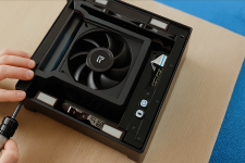 Das Bild zeigt das Innere der Tiny PS5 Redux, einer kompakten und modifizierten Version der PlayStation 5. In der kleinen Box sind verschiedene Komponenten sichtbar, darunter ein großer Lüfter zur Kühlung und eine Platine mit Anschlüssen für USB-Ports sowie steuerbare Knöpfe. Die Innenausstattung wirkt modern und durchdacht, mit einem Fokus auf effiziente Kühlung und Benutzerfreundlichkeit. Die Hintergrundfarbe ist blau und die gesamte Szene vermittelt einen technischen und handwerklichen Eindruck. Das Bild zeigt das Innere der Tiny PS5 Redux, einer kompakten und modifizierten Version der PlayStation 5. In der kleinen Box sind verschiedene Komponenten sichtbar, darunter ein großer Lüfter zur Kühlung und eine Platine mit Anschlüssen für USB-Ports sowie steuerbare Knöpfe. Die Innenausstattung wirkt modern und durchdacht, mit einem Fokus auf effiziente Kühlung und Benutzerfreundlichkeit. Die Hintergrundfarbe ist blau und die gesamte Szene vermittelt einen technischen und handwerklichen Eindruck.