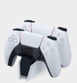 Das Bild zeigt eine PlayStation 5 DualSense Ladestation. Darauf sind zwei Controller platziert, die in einem eleganten Design auf einem stabilen Sockel stehen. Die Controller sind überwiegend weiß mit schwarzem Layout an den Griffen und Tasten. Der Hintergrund ist schlicht und neutral gehalten, sodass die Controller und die Ladestation im Fokus stehen. Diese Anordnung spiegelt das moderne und stilvolle Design von PlayStation-Produkten wider und wird von Gamern geschätzt, um ihre Ausrüstung organisiert und aufgeladen zu halten.