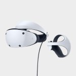 Das Bild zeigt ein modern gestaltetes VR-Headset in einem eleganten weißen Design, das zusammen mit einem passenden Controller präsentiert wird. Das Headset weist eine glatte Oberfläche und mehrere Sensoren auf, während der Controller eine ergonomische Form hat, die die Benutzerfreundlichkeit betont. Diese Geräte sind auf einem neutralen Hintergrund positioniert, was den Fokus auf das elegante Design und die technischen Details lenkt. Das Bild vermittelt den Eindruck von technologischem Fortschritt und verbesserten Gaming-Erlebnissen, passend zum Jubiläum der PlayStation 5.