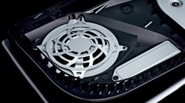Das Bild zeigt das Innere einer PlayStation 5, speziell die Kühlungskomponenten. Im Mittelpunkt steht ein großer silberner Lüfter, der für die Luftzirkulation und Kühlung der Konsole verantwortlich ist. Um den Lüfter herum sind verschiedene Teile des Gehäuses sichtbar, die speziell für eine effiziente Wärmeableitung ausgelegt sind. Die Gestaltung ist modern und technisch, wobei die Anordnung der Komponenten darauf abzielt, die hohe Leistung der Konsole optimal zu unterstützen.