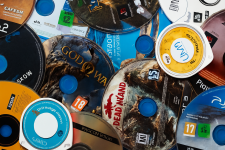 Das Bild zeigt eine Vielzahl von Spiel-DVDs und -Blu-rays, die sich übereinander stapeln. In der Mitte erkennt man deutlich die Cover von bekannten Spielen wie God of War und Dead Island. Die Medien sind in verschiedenen Formaten angeordnet, darunter PS2, PS3 und PS4, was auf eine breite Sammlung von Spielen hinweist. Die verschiedenen Logos und Designs der Discs verleihen dem Bild eine lebendige, bunte Ausstrahlung und vermitteln die Leidenschaft für das Gaming.