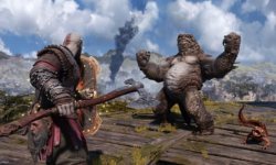 Das Bild zeigt eine Szene aus einem Action-Adventure-Spiel, in der der Protagonist Kratos mit seiner charakteristischen Waffe, einer Axt, konfrontiert wird. Gegenüber steht ein kräftiger, kreaturenähnlicher Gegner, der eine drohende Pose einnimmt. Im Hintergrund ist eine weitläufige Landschaft mit Bergen und einem wolkigen Himmel zu sehen. Diese Darstellung vermittelt eine spannende und dynamische Atmosphäre, die die Herausforderung von Kämpfen und das Eintauchen in eine epische Geschichte unterstreicht.