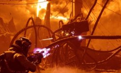 Das Bild zeigt eine düstere, postapokalyptische Landschaft, dominiert von einem tiefen, orangen Licht. In der Szene ist ein Mann zu sehen, der einen futuristischen Blaster hält und dabei auf mehrere mechanische Objekte zielt. Die Umgebung wirkt chaotisch, mit zerklüfteten Strukturen und einem bedrohlichen Himmel, der von hohen, metallischen Elementen sowie roten und orangefarbenen Tönen durchzogen ist. Die Atmosphäre vermittelt ein Gefühl von Gefahr und Action, das typisch für Sci-Fi-Spiele ist.