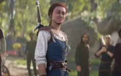 Das Bild zeigt eine Figur aus einem Fantasy-Setting, die in einem blauen Kleid mit einem Schwert auf dem Rücken steht. Die Person hat braune Haare und schaut mit einem interessierten und leicht besorgten Ausdruck. Im Hintergrund sind mehrere Personen zu sehen, die ebenfalls auf die Szenerie fokussiert scheinen, was eine zentrale Handlung andeutet. Die Umgebung wirkt lebendig und grün, was auf eine natürliche Umgebung hinweist. Insgesamt vermittelt das Bild den Eindruck eines wichtigen Moments in einer Geschichte oder einem Abenteuer.