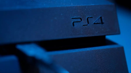 Das Bild zeigt einen Ausschnitt einer PlayStation 4 Konsole, bei dem das Logo PS4 klar erkennbar ist. Die Beleuchtung kreiert eine dunkle, nahezu mysteriöse Atmosphäre, die den technischen Charakter der Konsole unterstreicht. Die Oberfläche scheint glatt und leicht strukturiert zu sein, wobei Kontraste zwischen Licht und Schatten die Eleganz des Designs hervorheben. Es vermittelt ein Gefühl von Nostalgie und erinnert an die früheren Zeiten des Gaming mit dieser beliebten Konsole.
